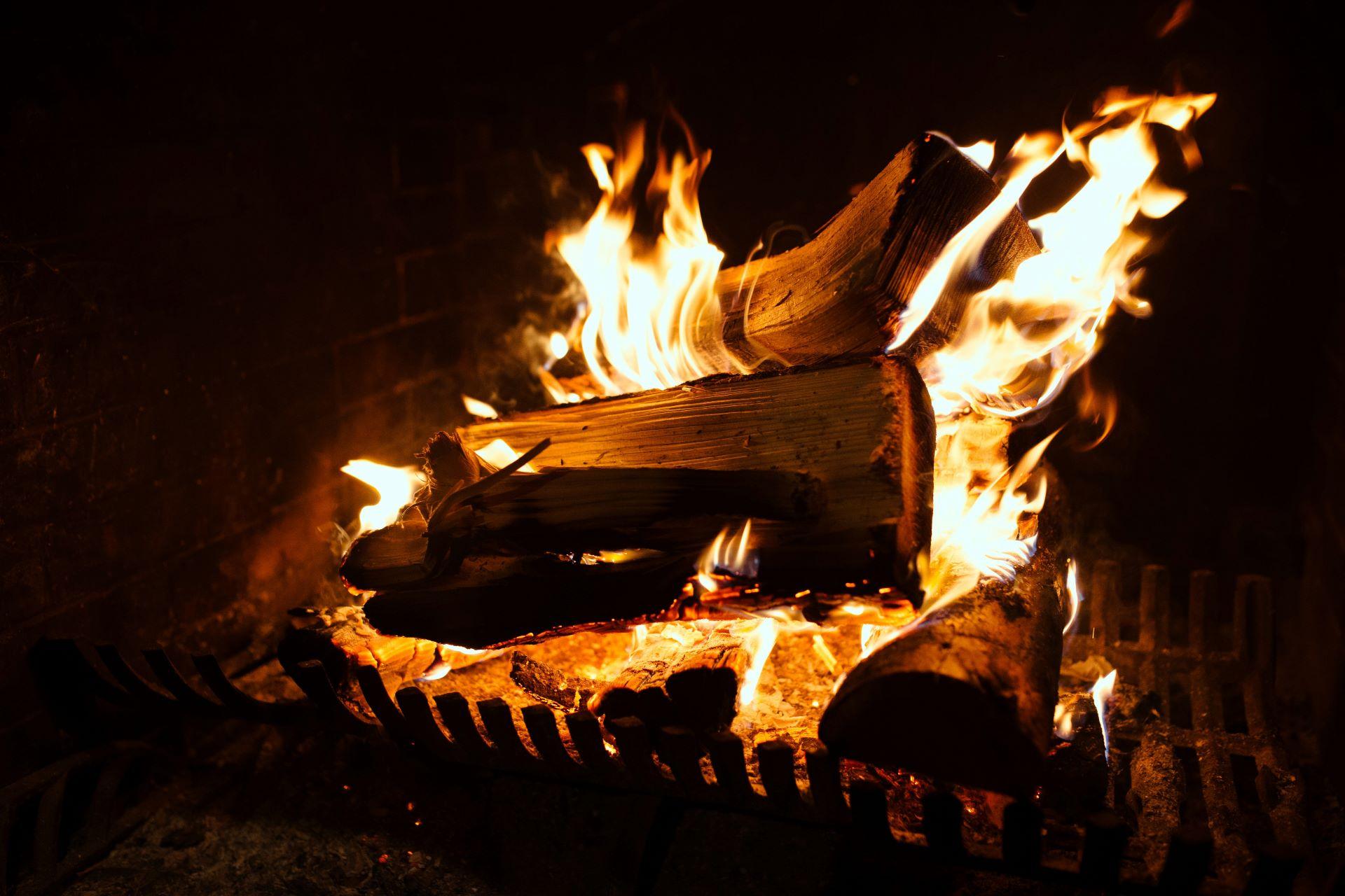 Nahaufnahme von brennendem Holz im Kamin mit lodernden Flammen, die eine gemütliche Atmosphäre erzeugen.