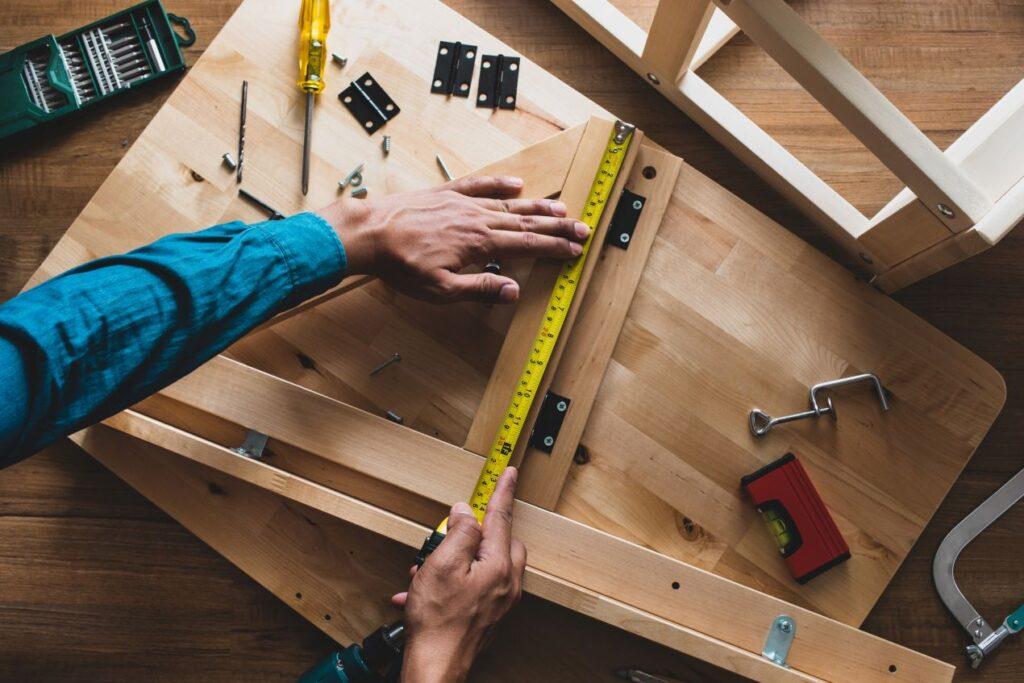 Detailaufnahme eines Handwerkers beim Vermessen von Holzplatten im moebelbau berlin mit professionellem Werkzeug